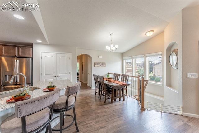 dining area with vaulted ceiling, hardwood / wood-style floors, and a chandelier