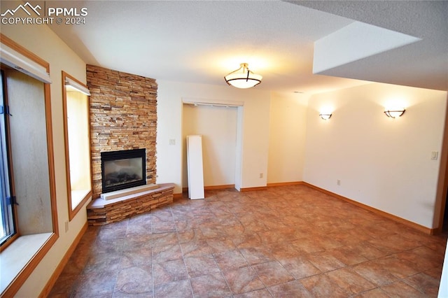 unfurnished living room with a textured ceiling and a stone fireplace