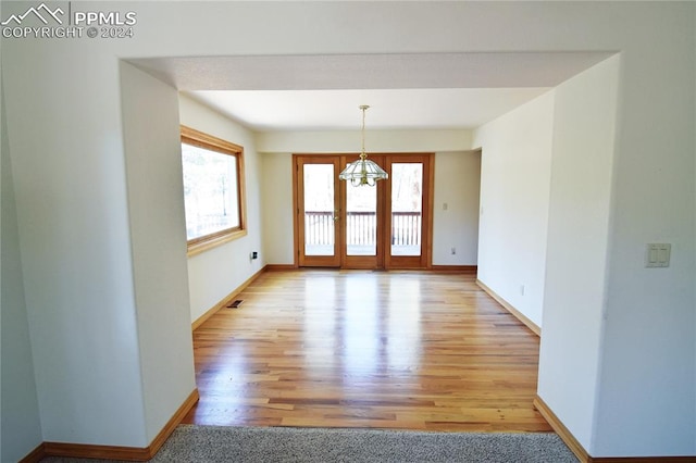 unfurnished room with light wood-type flooring and a notable chandelier