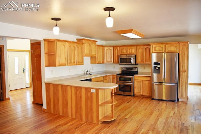 kitchen featuring light wood-type flooring, pendant lighting, kitchen peninsula, and stainless steel appliances