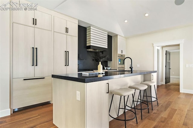 kitchen featuring a kitchen island with sink, sink, and light hardwood / wood-style flooring