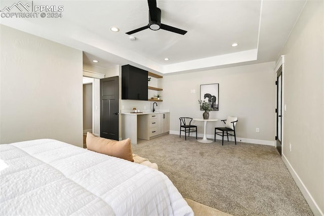 bedroom with light carpet, a tray ceiling, ceiling fan, and sink