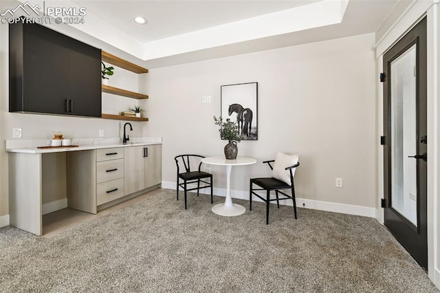 bar with a tray ceiling, light carpet, and sink