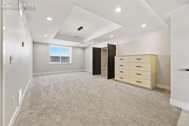 unfurnished bedroom with light carpet and a tray ceiling