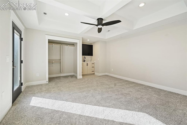 unfurnished bedroom featuring carpet, beam ceiling, a closet, and ceiling fan