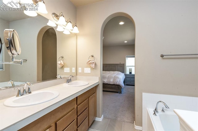 bathroom with a tub to relax in, vanity, and tile patterned floors