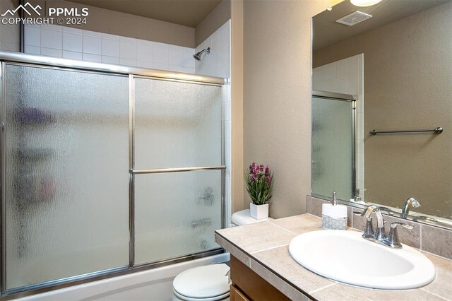 full bathroom featuring shower / bath combination with glass door, toilet, and vanity