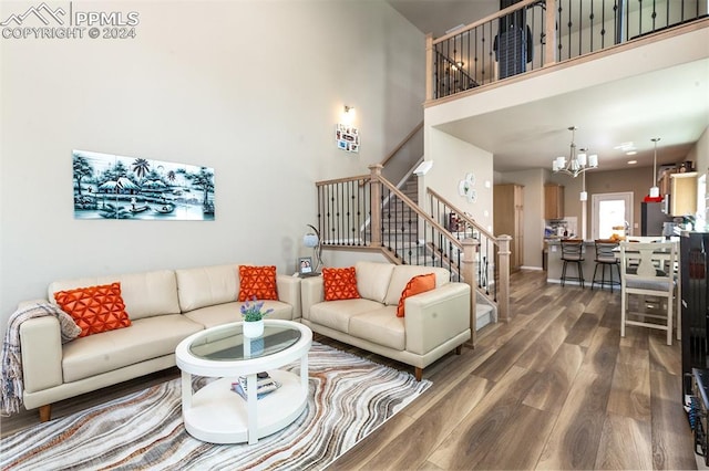 living room featuring dark wood-type flooring, a notable chandelier, and a towering ceiling