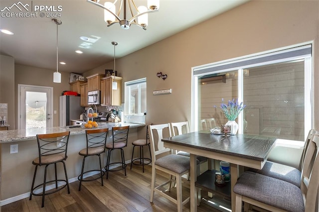 dining space featuring dark wood-type flooring, an inviting chandelier, and sink