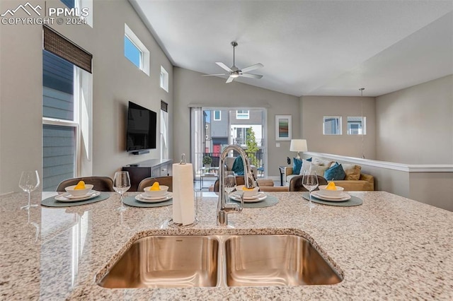 kitchen featuring ceiling fan, sink, light stone countertops, and vaulted ceiling