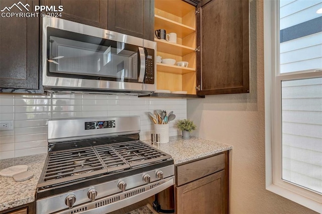 kitchen with light stone counters, dark brown cabinetry, appliances with stainless steel finishes, and tasteful backsplash