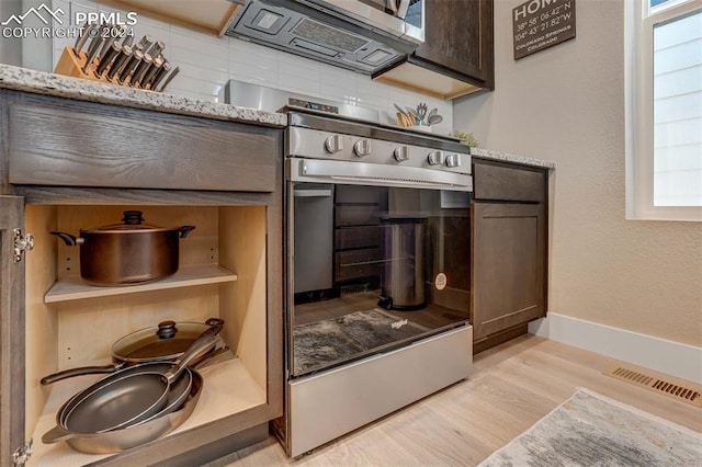 kitchen featuring light wood-type flooring, tasteful backsplash, stainless steel appliances, light stone countertops, and dark brown cabinetry