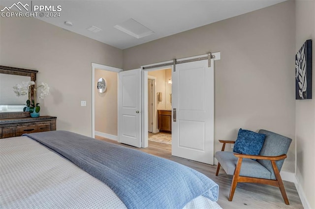 bedroom with a barn door and hardwood / wood-style flooring