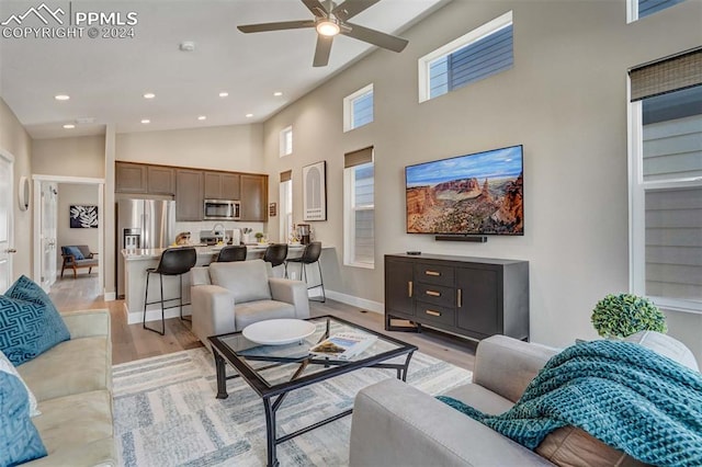 living room featuring high vaulted ceiling, ceiling fan, and light hardwood / wood-style flooring