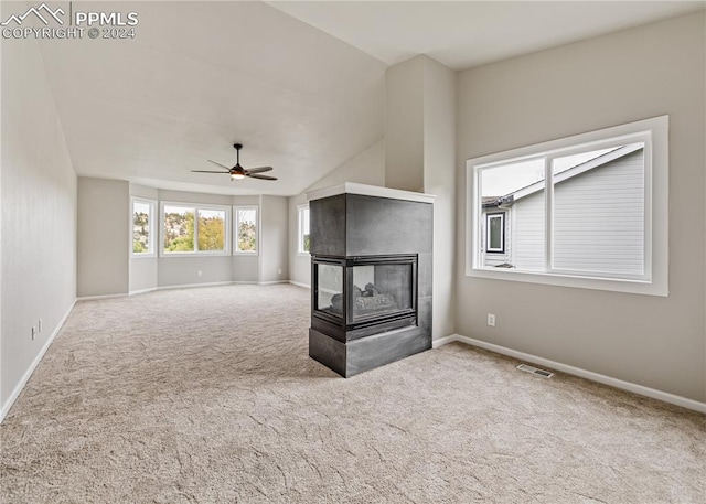 unfurnished living room featuring carpet floors, a multi sided fireplace, vaulted ceiling, and ceiling fan