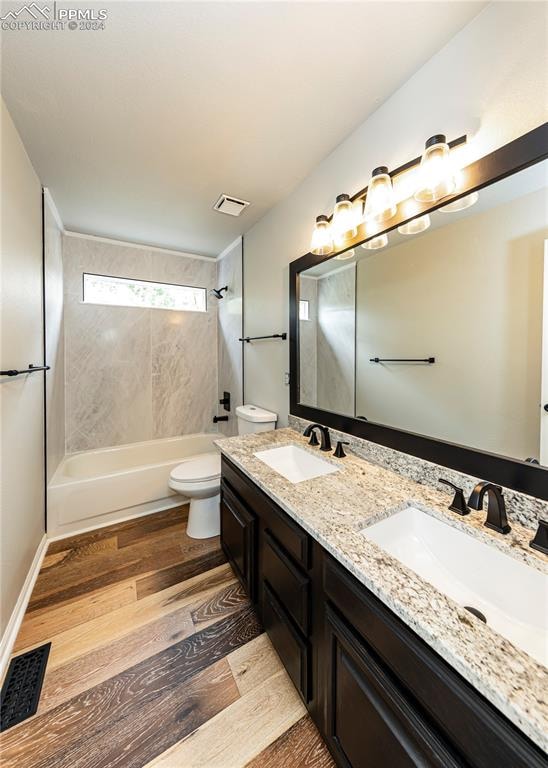 full bathroom with tiled shower / bath combo, vanity, hardwood / wood-style floors, and toilet