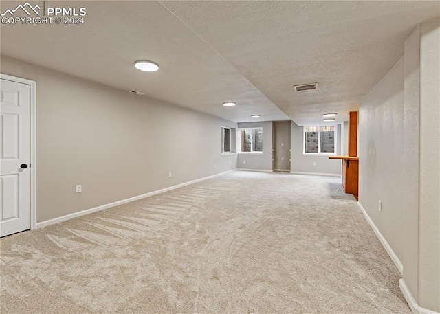 basement with light colored carpet and a textured ceiling