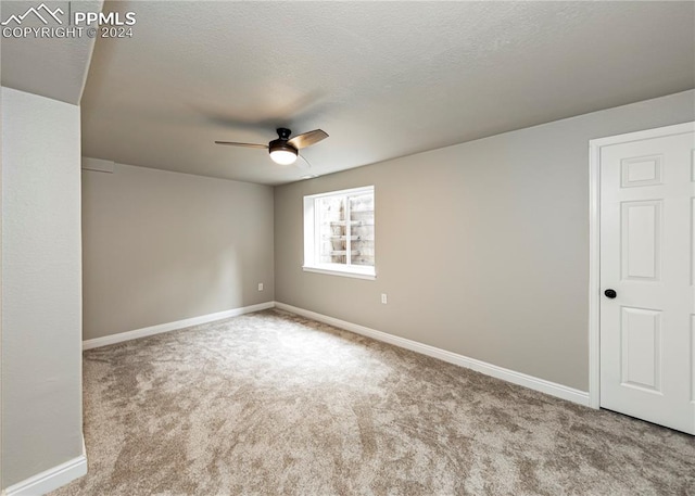 spare room with a textured ceiling, ceiling fan, and light colored carpet