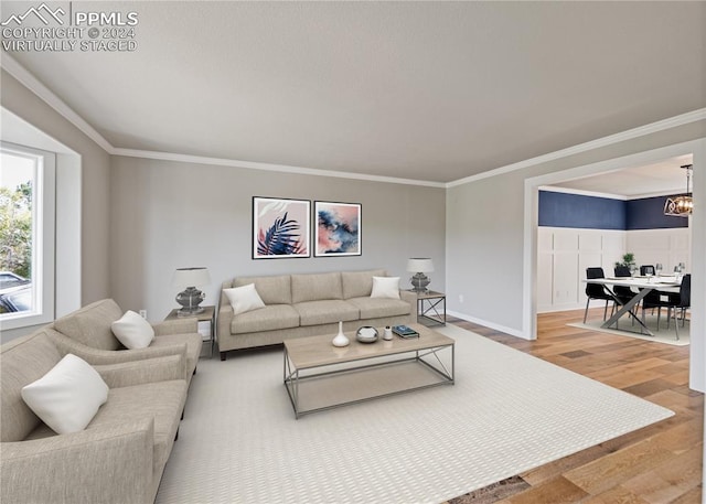 living room with wood-type flooring, crown molding, and a chandelier