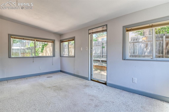 carpeted empty room featuring vaulted ceiling