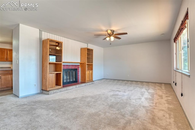 unfurnished living room with light carpet, ceiling fan, and a tiled fireplace