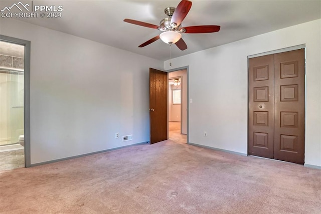 unfurnished bedroom featuring ceiling fan, ensuite bathroom, light carpet, and a closet