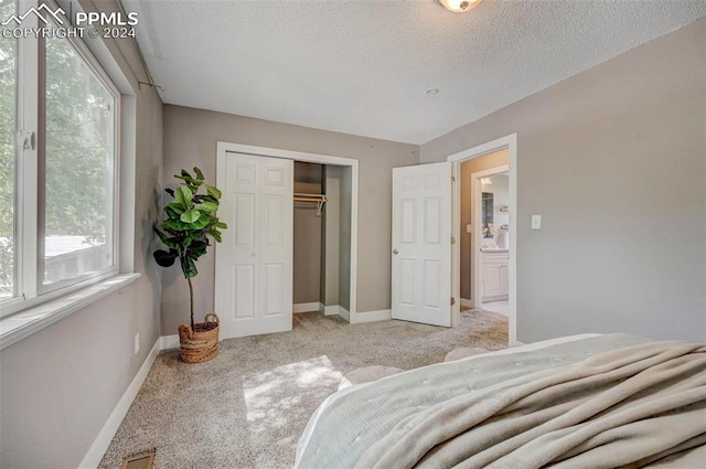 carpeted bedroom featuring a textured ceiling and a closet