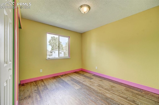 empty room featuring a textured ceiling and hardwood / wood-style flooring