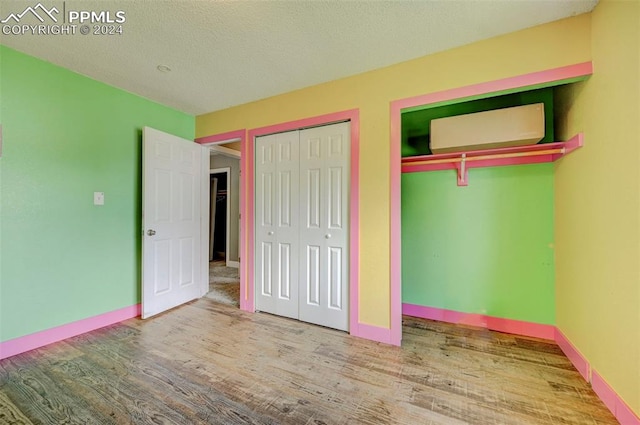 unfurnished bedroom featuring a textured ceiling, two closets, and hardwood / wood-style flooring