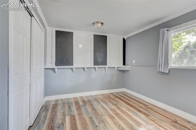 spare room featuring wood-type flooring and crown molding