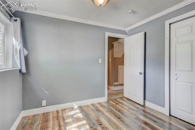 unfurnished bedroom with ornamental molding and light wood-type flooring