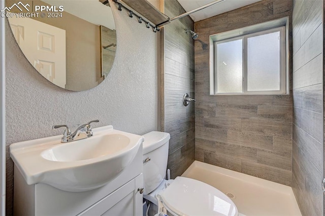 bathroom featuring vanity, toilet, and a tile shower