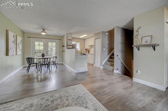 interior space with french doors, ceiling fan, a textured ceiling, and light hardwood / wood-style flooring