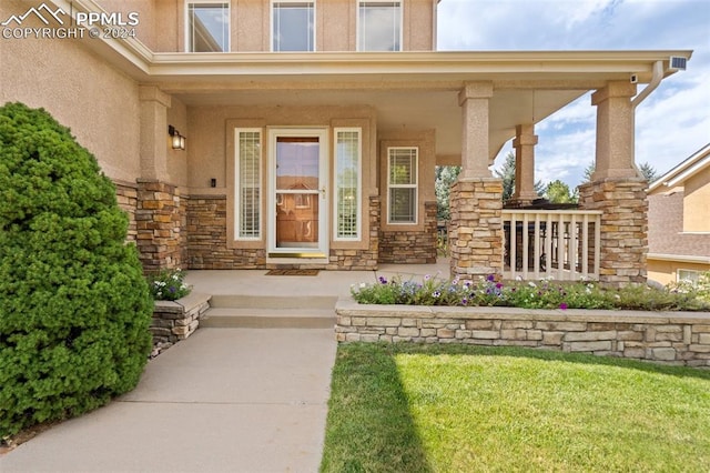 entrance to property with a yard and covered porch