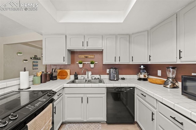 kitchen featuring black appliances, white cabinetry, and tile countertops