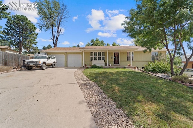 ranch-style home featuring a garage, a front yard, and covered porch