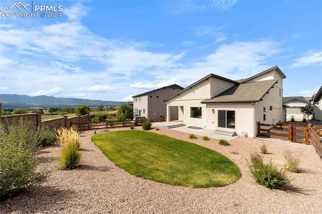 rear view of house with a mountain view, a lawn, and a patio