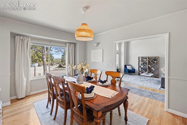 dining area with ornamental molding and light hardwood / wood-style flooring