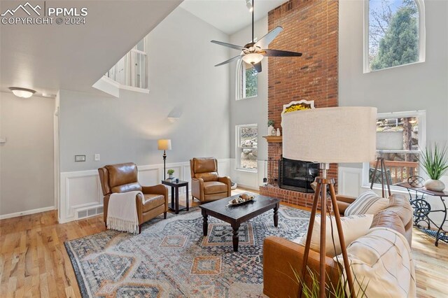 living room featuring a towering ceiling, hardwood / wood-style flooring, and ceiling fan