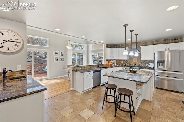 kitchen featuring hanging light fixtures, stainless steel appliances, white cabinetry, sink, and kitchen peninsula