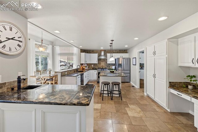 kitchen with dark stone countertops, appliances with stainless steel finishes, white cabinetry, and a kitchen island