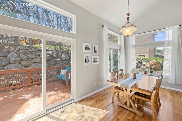 dining room with light wood-type flooring and high vaulted ceiling