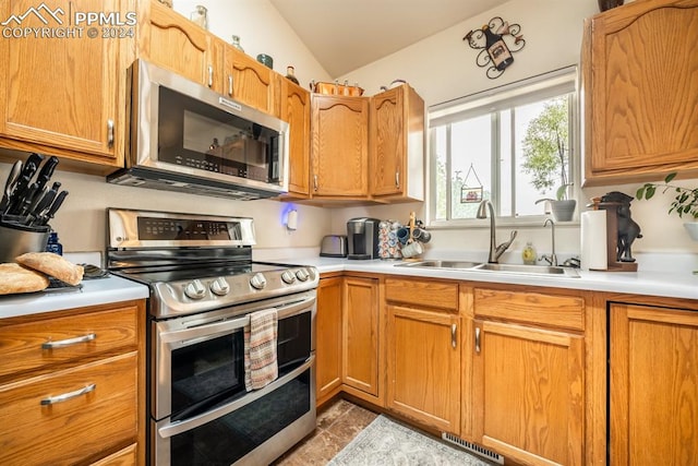 kitchen with stainless steel appliances, sink, light tile patterned flooring, and vaulted ceiling