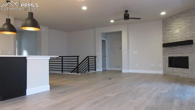 unfurnished living room with ceiling fan, a fireplace, and light hardwood / wood-style floors