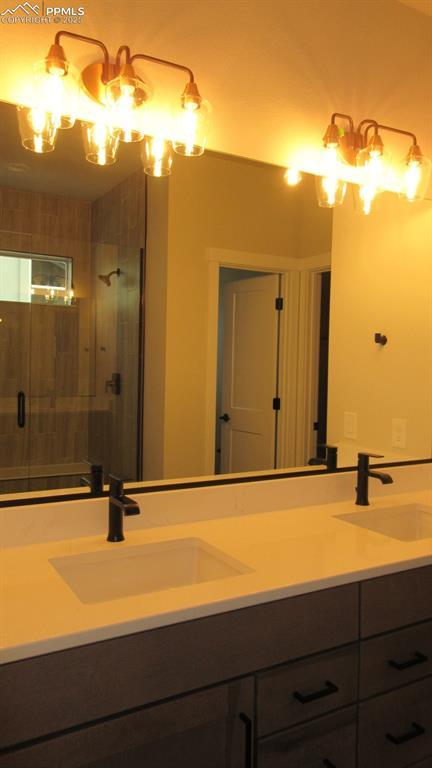 bathroom with an inviting chandelier, vanity, and a shower with door