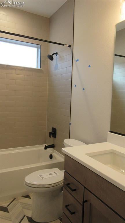 full bathroom with tiled shower / bath, vanity, and toilet