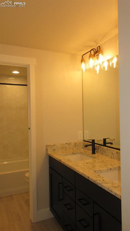 full bathroom featuring vanity, tiled shower / bath combo, and toilet