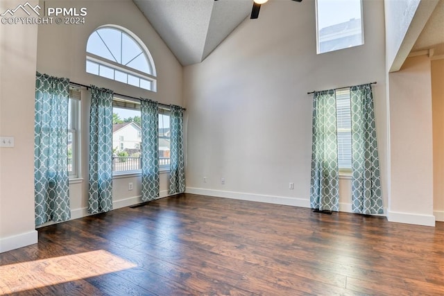 unfurnished room with a healthy amount of sunlight, dark hardwood / wood-style flooring, and high vaulted ceiling