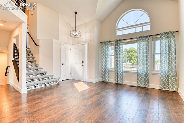 foyer entrance featuring dark hardwood / wood-style flooring, high vaulted ceiling, and an inviting chandelier