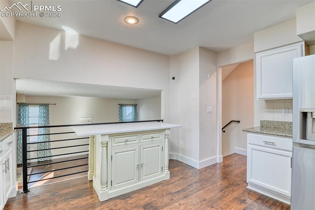 kitchen featuring a kitchen island, light stone counters, dark hardwood / wood-style flooring, white refrigerator with ice dispenser, and white cabinets